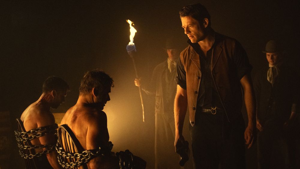 James Norton as Sean with two prisoners tied to a chair