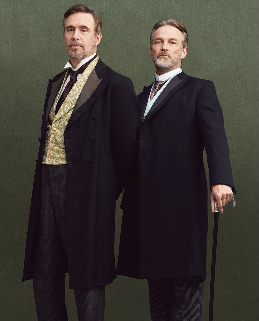 Two middle aged men in professional Victorian dark suits. 