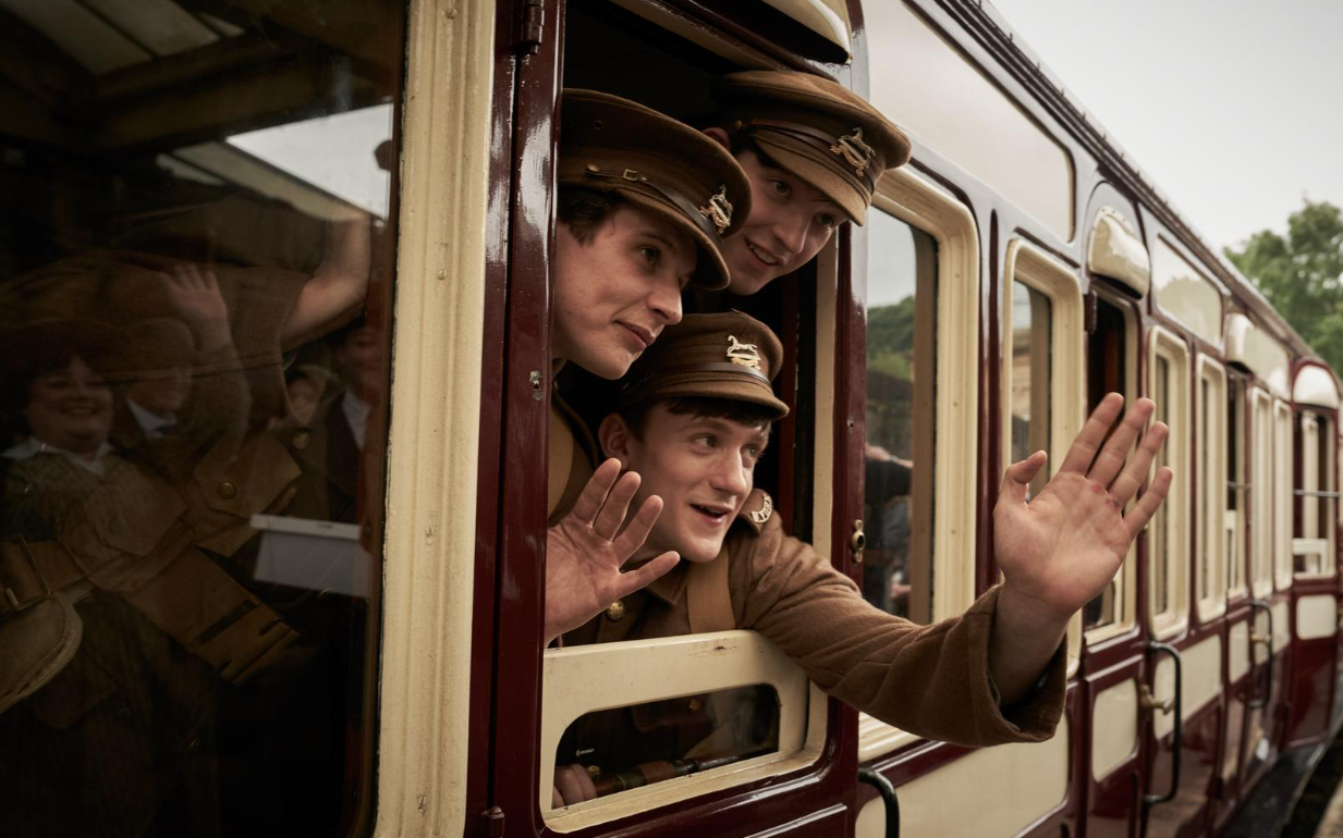 A group of young soldiers waving from a train