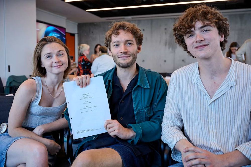 three cast members holding the script