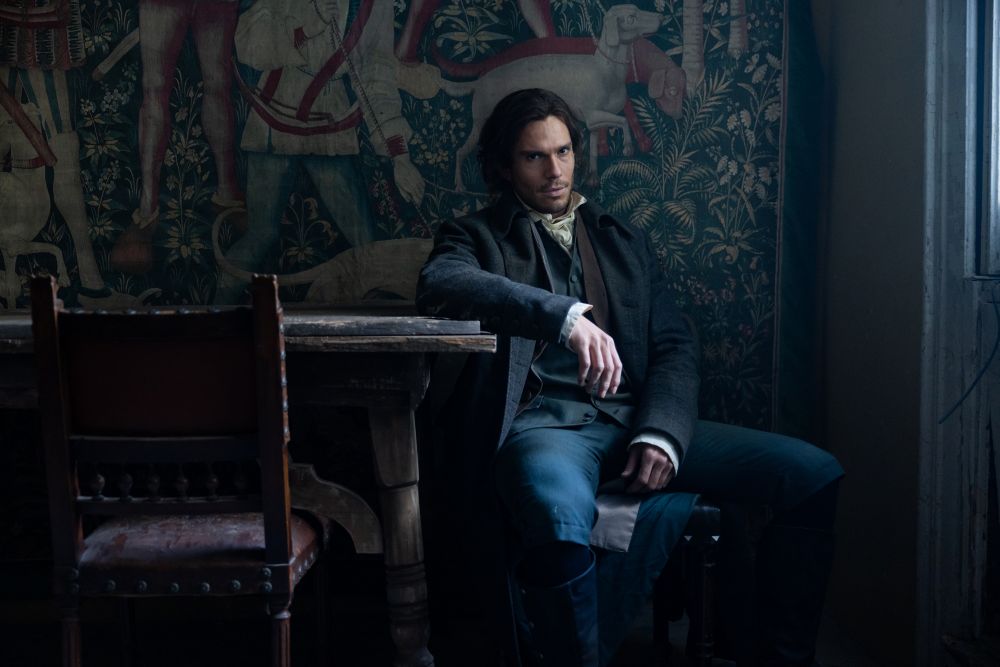 Charles Darney in a chair beside a desk in a dark room