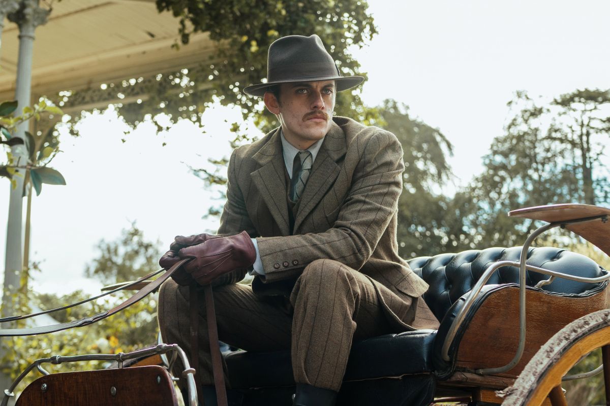 A man in suit and hat sitting in a carriage