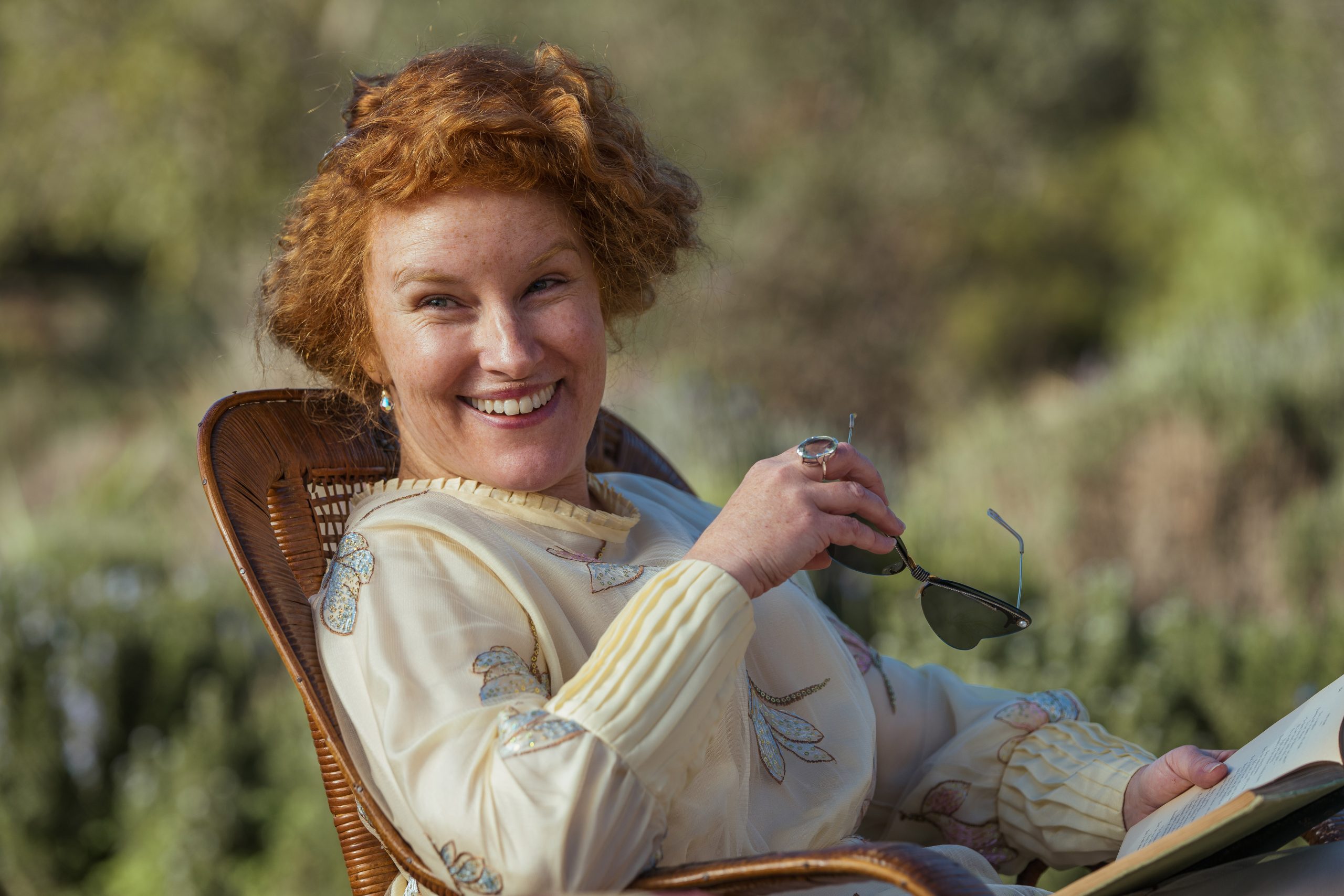 augusta a red haired woman seated and smiling