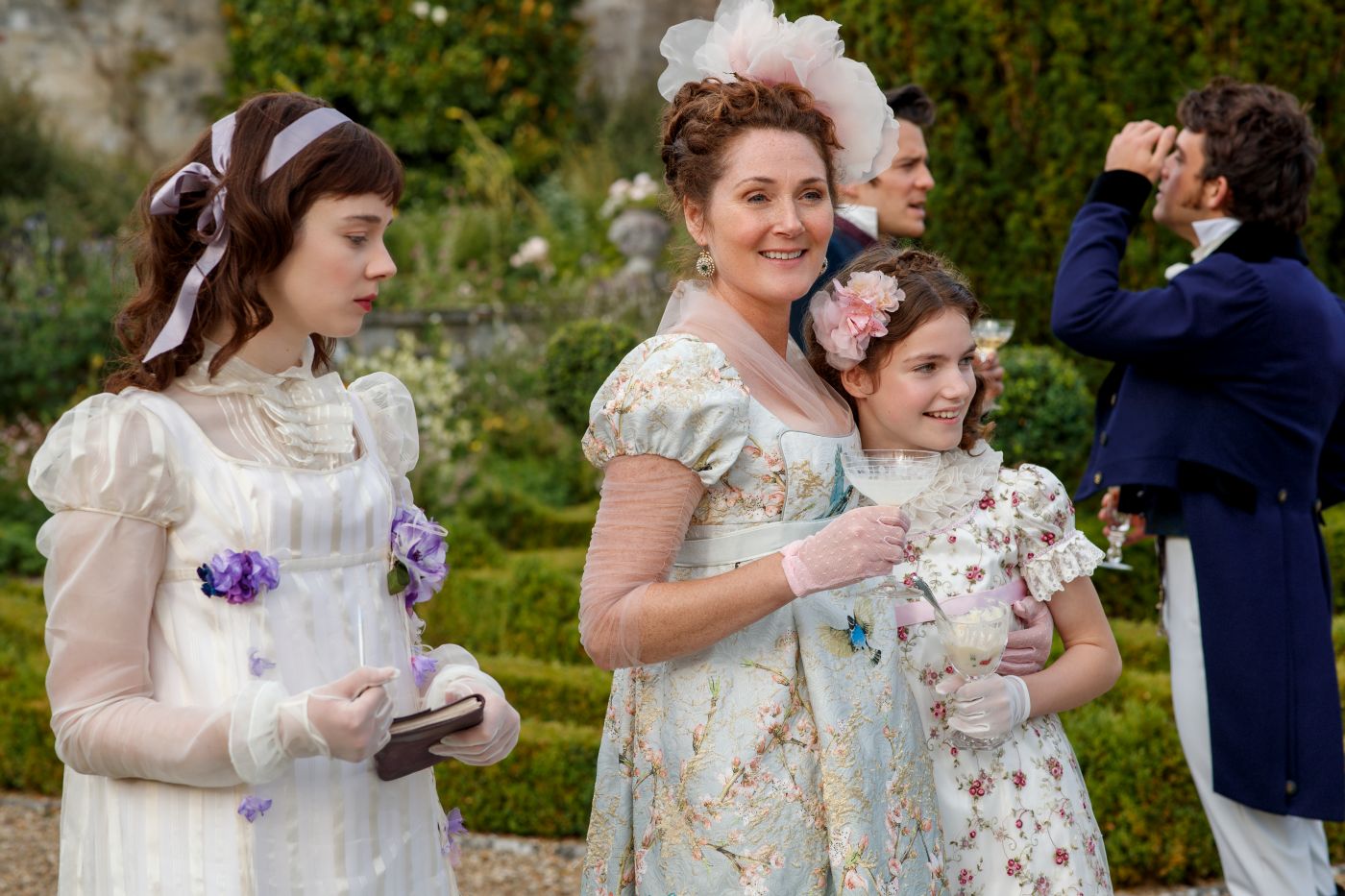 Eloise Bridgerton stands beside Violet and Hyacinth Bridgerton at an outdoor gathering in Bridgerton Season 1 Episode 6.