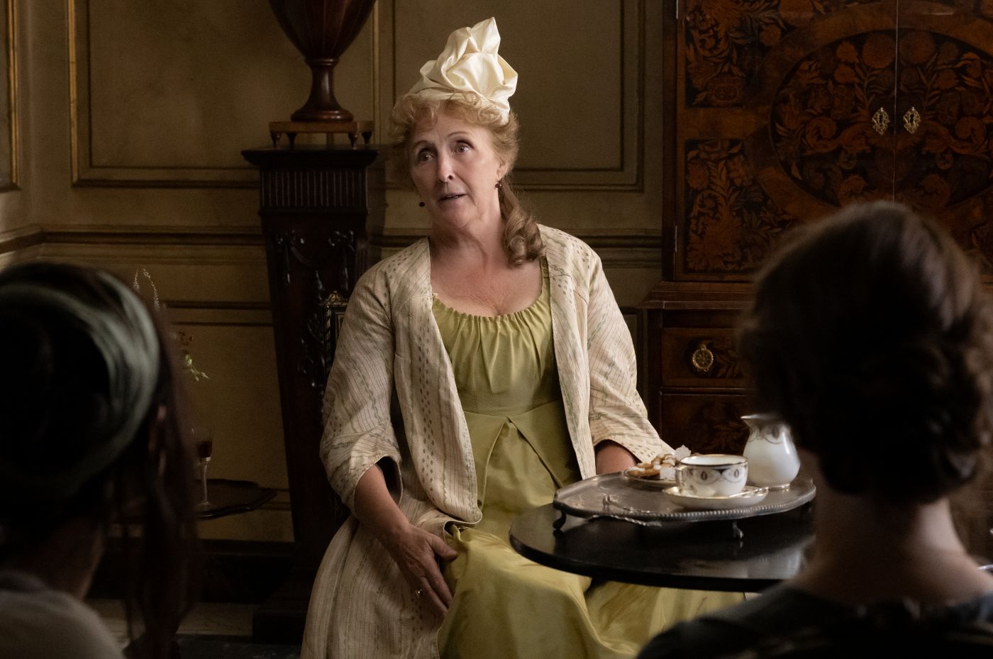 Fiona Shaw as Mrs Jennings seated at a tea table in Sense and Sensibility.